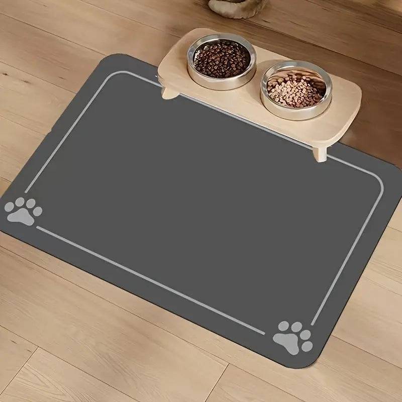 Dark gray absorbent pet feeding mat with a thin border line and paw prints in two corners under a raised double bowl.