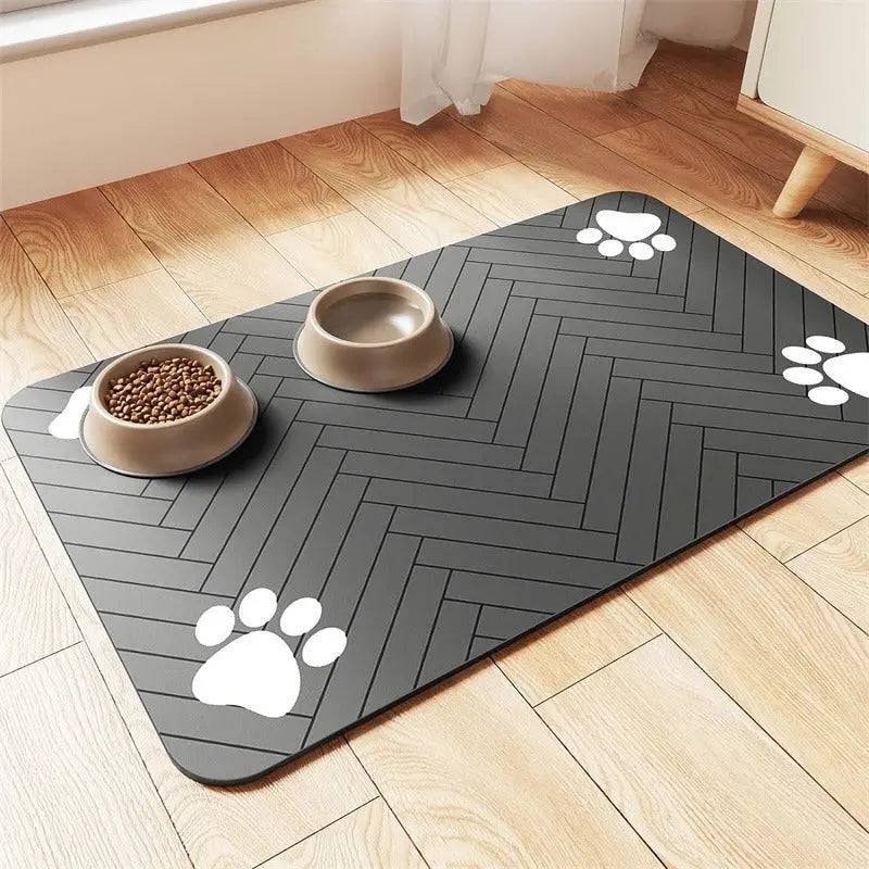 Dark gray chevron absorbent pet feeding mat with white paw prints, a food bowl and a water bowl.