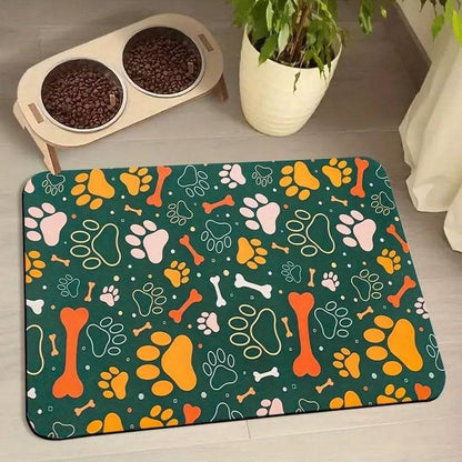 Dark green absorbent pet feeding mat with orange, yellow and white paws and bones under a raised double bowl.