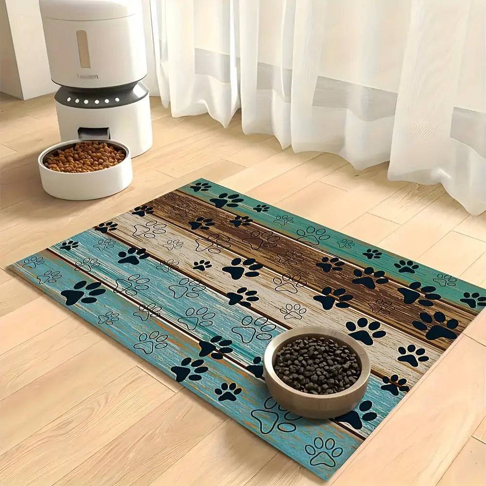 Teal and wood plank print absorbent pet feeding mat with black paw prints, in front of an automatic feeder.