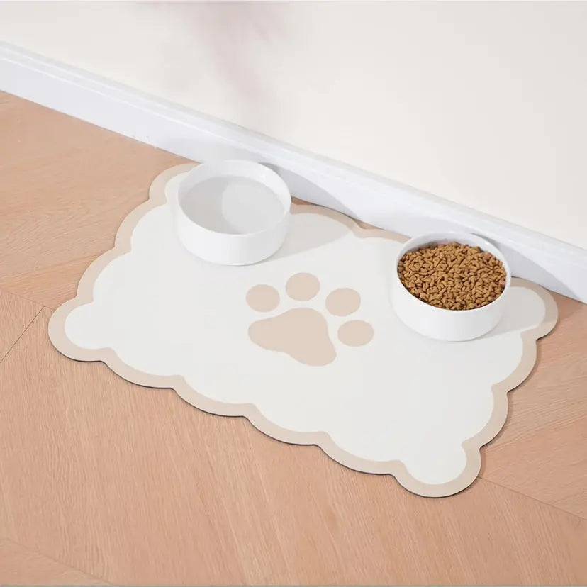 Cloud-shaped white absorbent pet feeding mat with a taupe paw print, a water bowl and a food bowl.