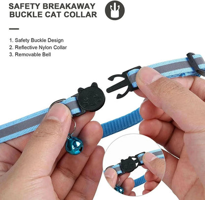 Hands pulling the safety breakaway buckle apart on the blue reflective AirTag cat collar, with the removable bell attached