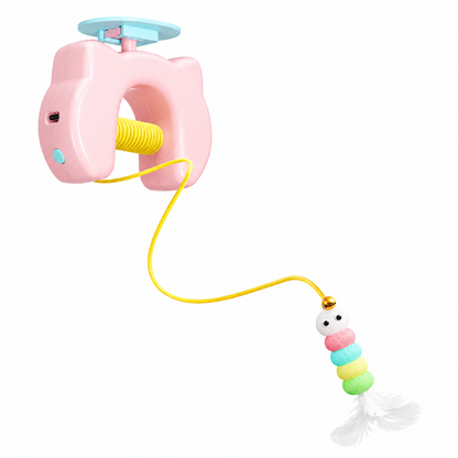 The pink Noblias automatic yo-yo cat toy with its ceiling mount and beaded feather teaser hanging on an elastic rope.