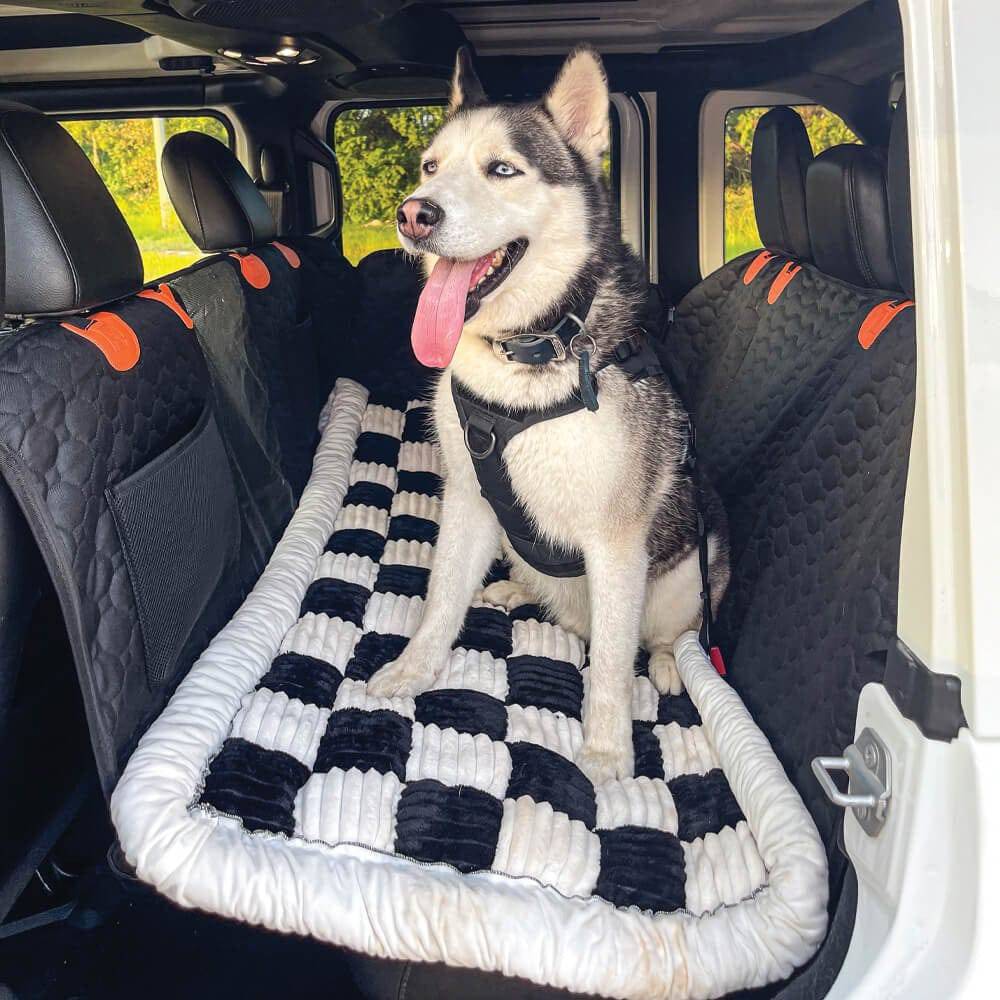 A husky stretched out asleep on the Noblias back seat dog bed mat during a car journey.