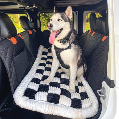 A husky stretched out asleep on the Noblias back seat dog bed mat during a car journey.