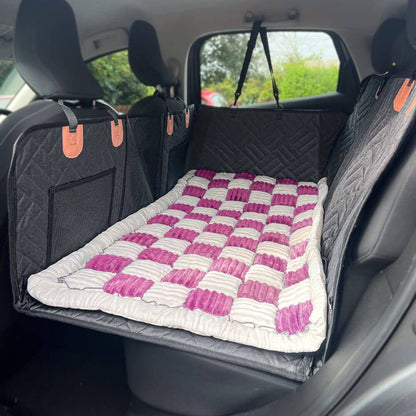 The Noblias back seat dog bed mat in the pink check style, laid across the rear seat.