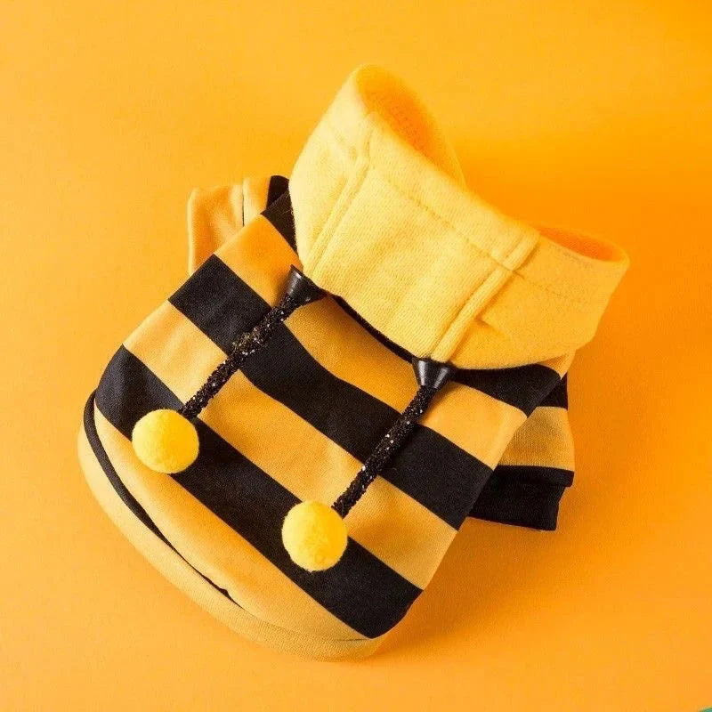 Bee costume hoodie laid flat on orange, showing the soft yellow fleece hood and pom pom antennae.