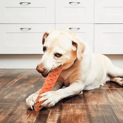Labrador lying on a hardwood floor chewing the braided rope carrot dog toy