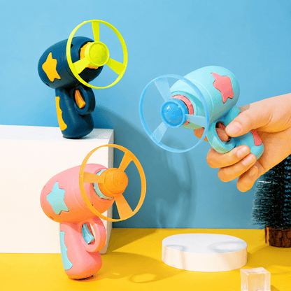 Mint and pink cat flying disc launchers on a yellow background with spinning three-blade discs, one held in a hand ready to fire