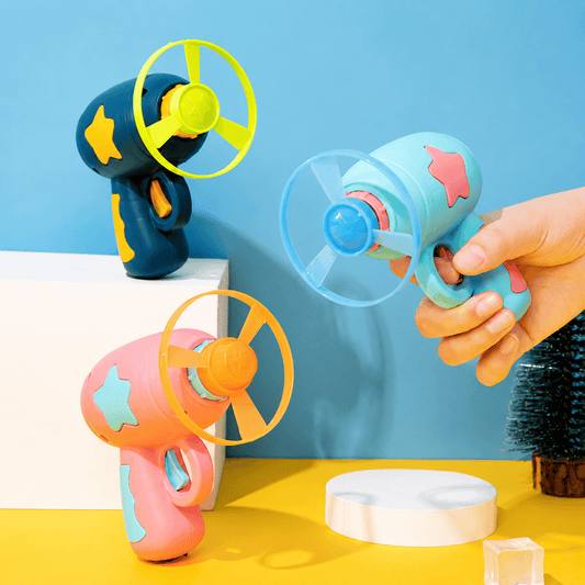 Mint and pink cat flying disc launchers on a yellow background with spinning three-blade discs, one held in a hand ready to fire
