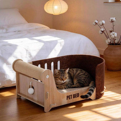 Tabby cat resting in the cat scratcher lounge bed in a sunlit bedroom with the dangling ball toy on the side
