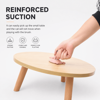A hand lifting a small wooden table by the suction base of the Noblias cat wand, showing how firmly the cup grips.