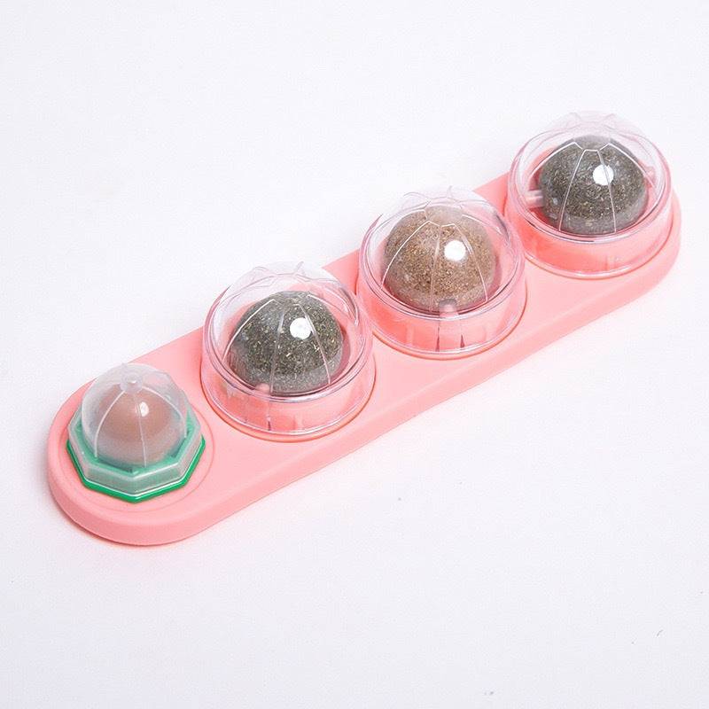 Pink Noblias catnip wall ball rail holding four rotating treat balls under clear covers.