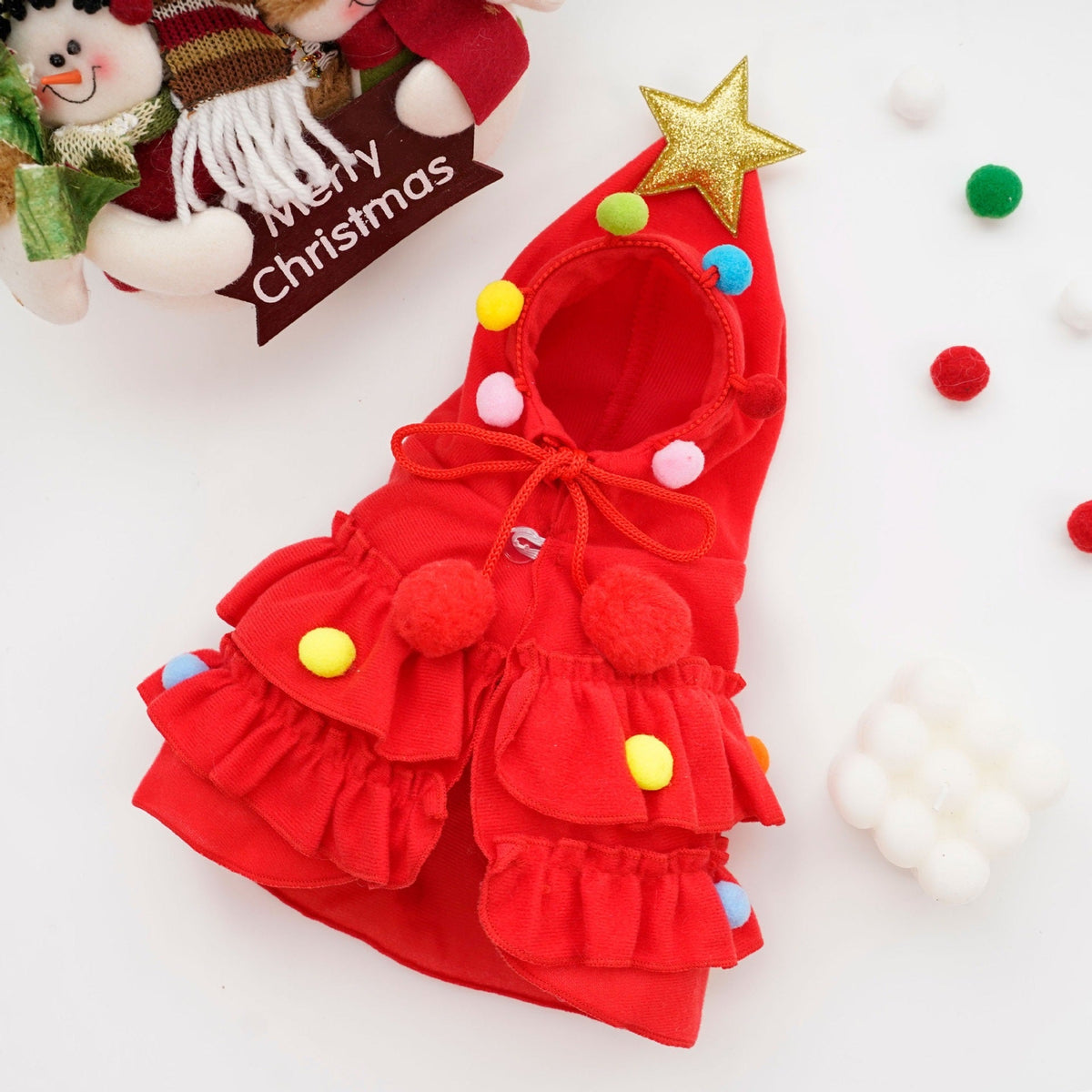 Red Christmas tree pet costume laid flat, showing the tiered ruffles, pom poms and gold star.