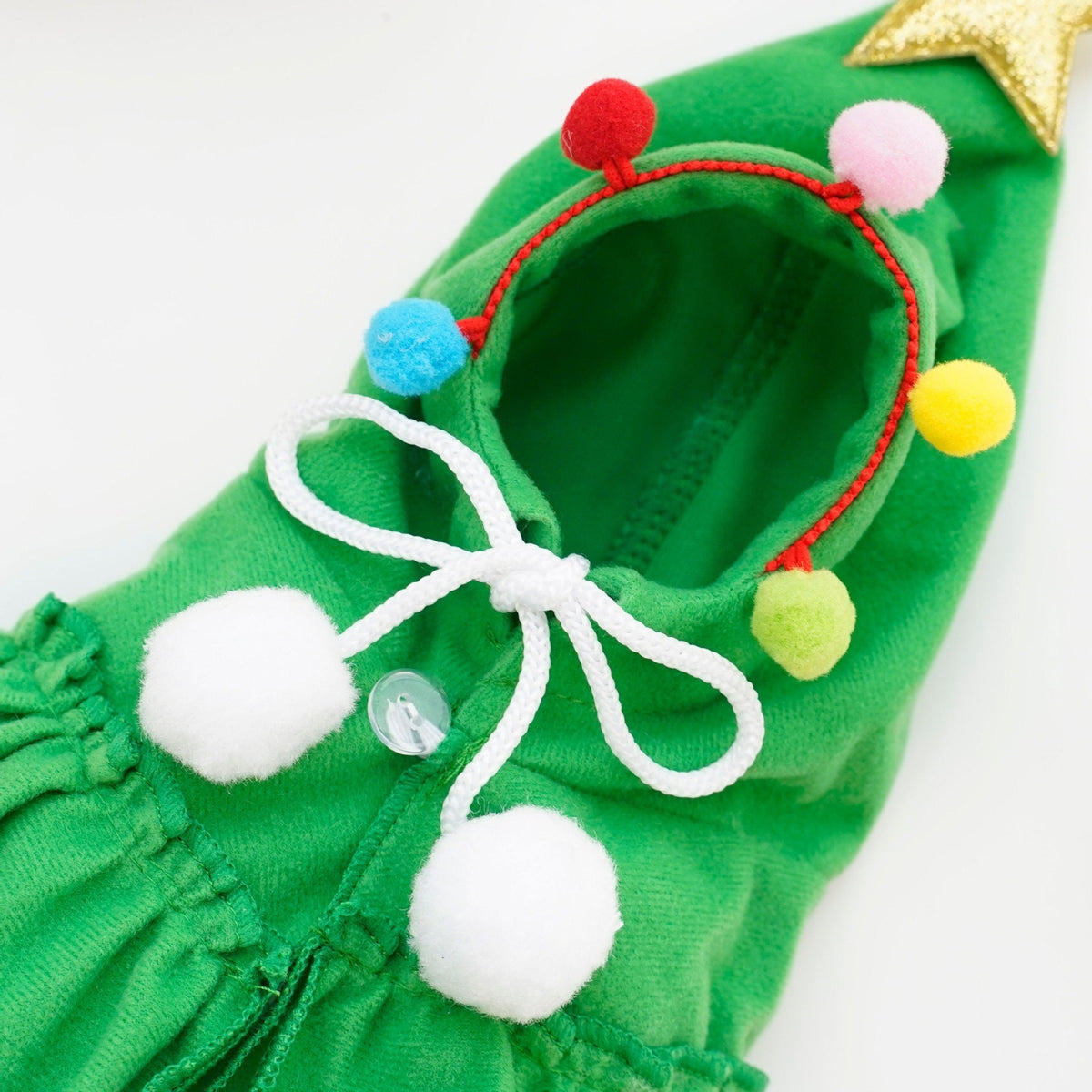 Close-up of the front ties and pom pom trim on the green Christmas tree pet costume hood.