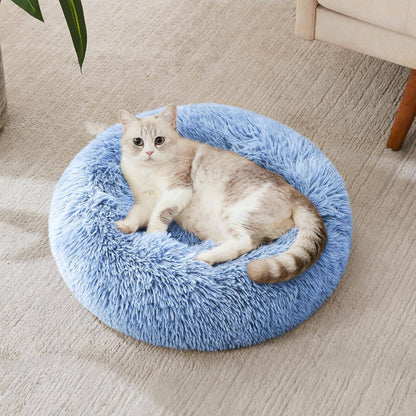 Cat stretched across the light blue Noblias cloud calming donut bed on a living room floor.