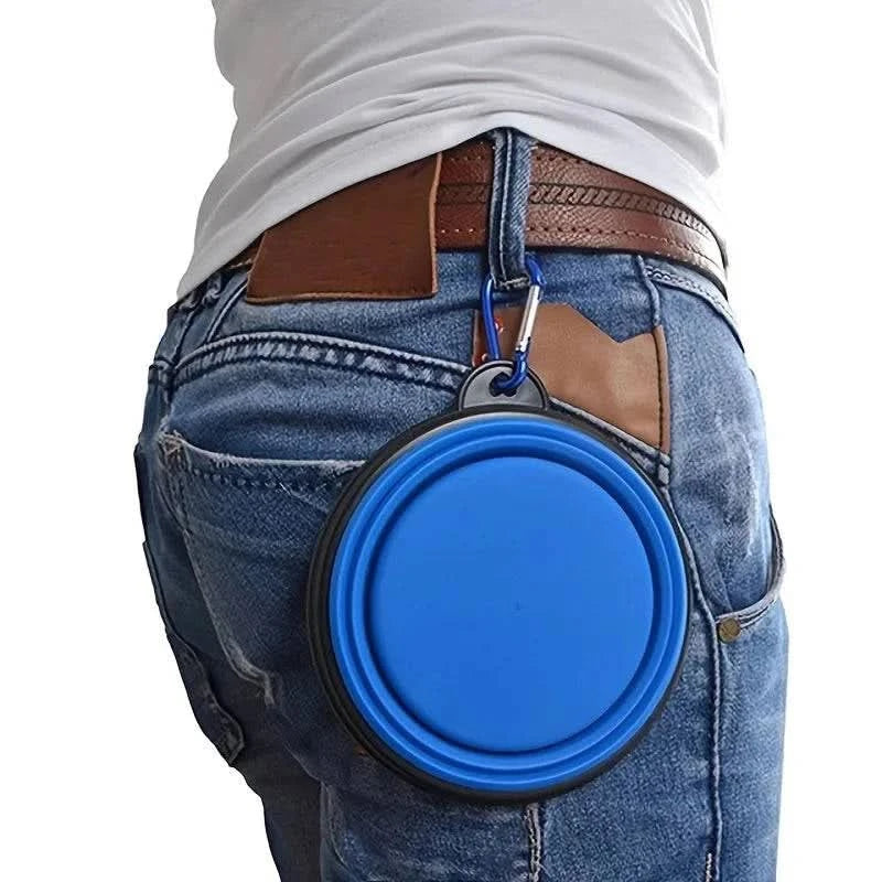 Blue Noblias collapsible silicone travel bowl clipped to a belt loop on a pair of jeans.