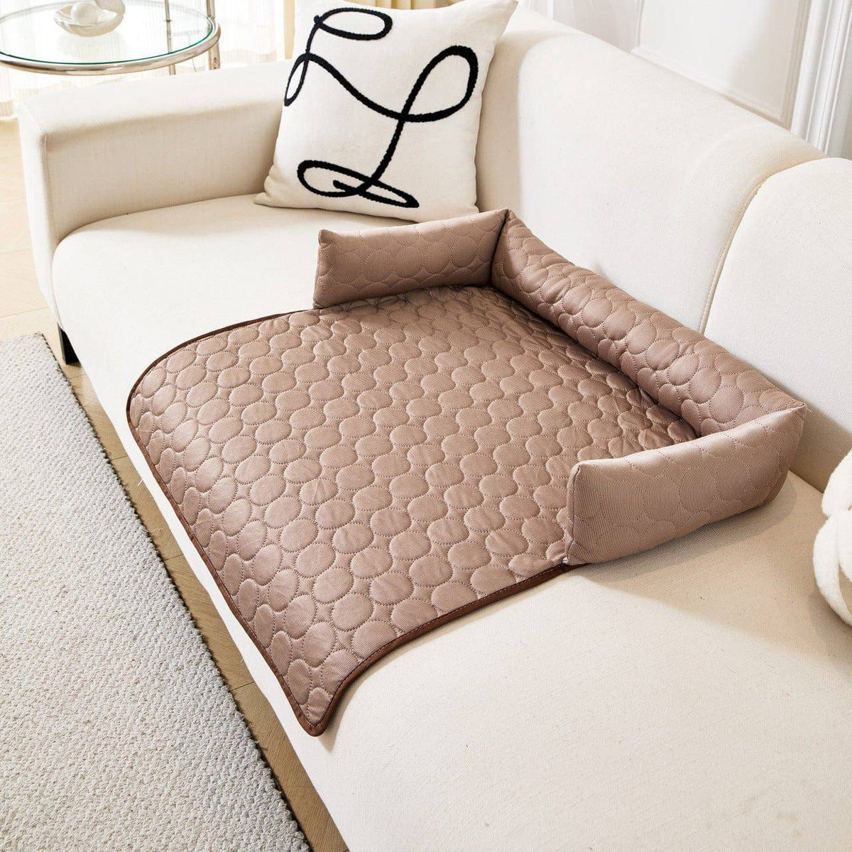 Beige Noblias cooling dog couch cover on a white sofa, with the bolster along the back and one side and the mat hanging over the seat edge.