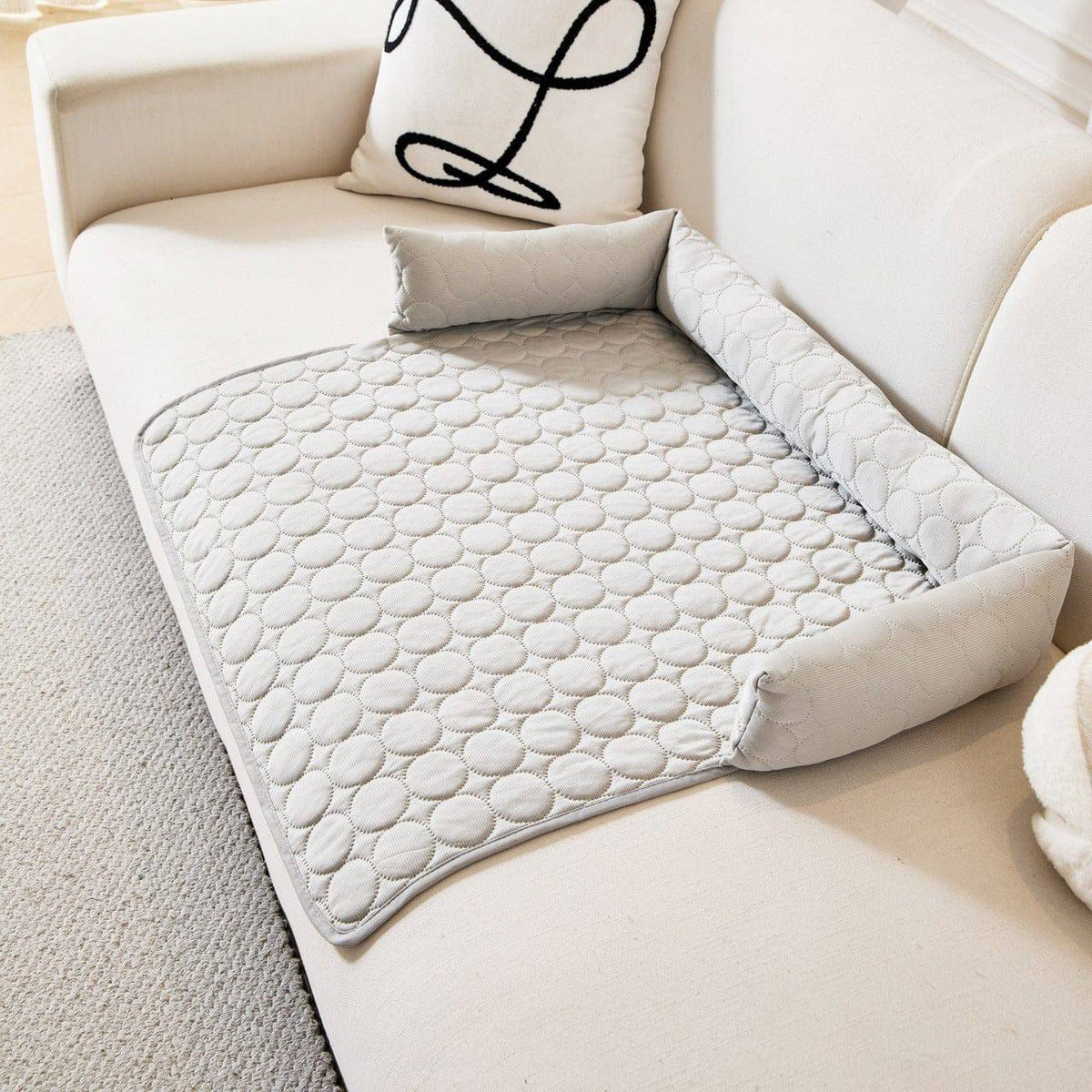 Gray Noblias cooling dog couch cover spread over a white sofa seat with the bolster back in place.