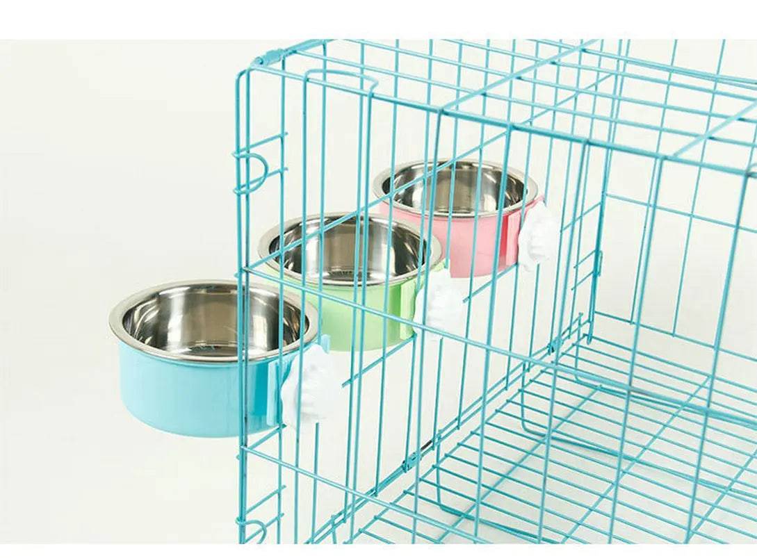Three crate bowls in blue, green and pink clamped side by side along the wire of a blue cage
