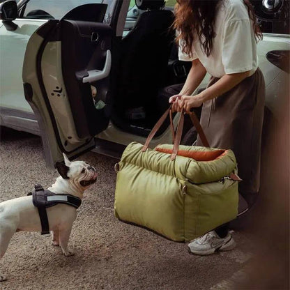 An owner lifting the green Noblias dog car seat bed by its handles beside an open car door.
