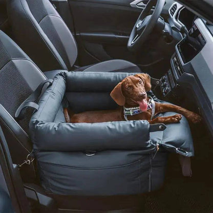 The gray Noblias dog car seat bed fitted on the front passenger seat with a small dog looking out.
