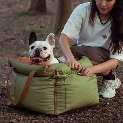 A french bulldog sitting in the green Noblias dog car seat bed outdoors with its owner alongside.