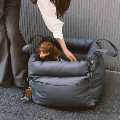 An owner lowering a dachshund into the gray Noblias dog car seat bed.