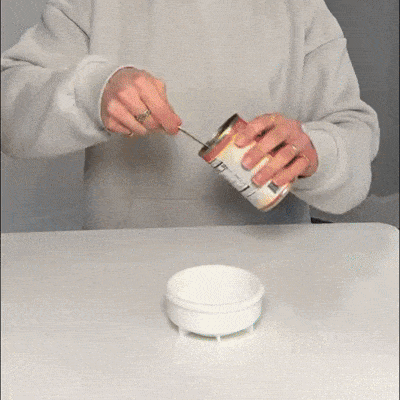 Animation of a corgi licking the blue dog lick bowl with rolling ball on a wood floor.