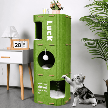 Green two layer Noblias felt cat house beside a bedside table with a cat reaching for the hanging pompom.