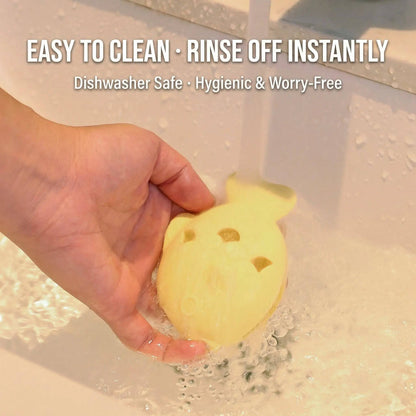 Hand rinsing the light yellow fish treat dispenser toy under running water, labeled easy to clean, dishwasher safe and hygienic