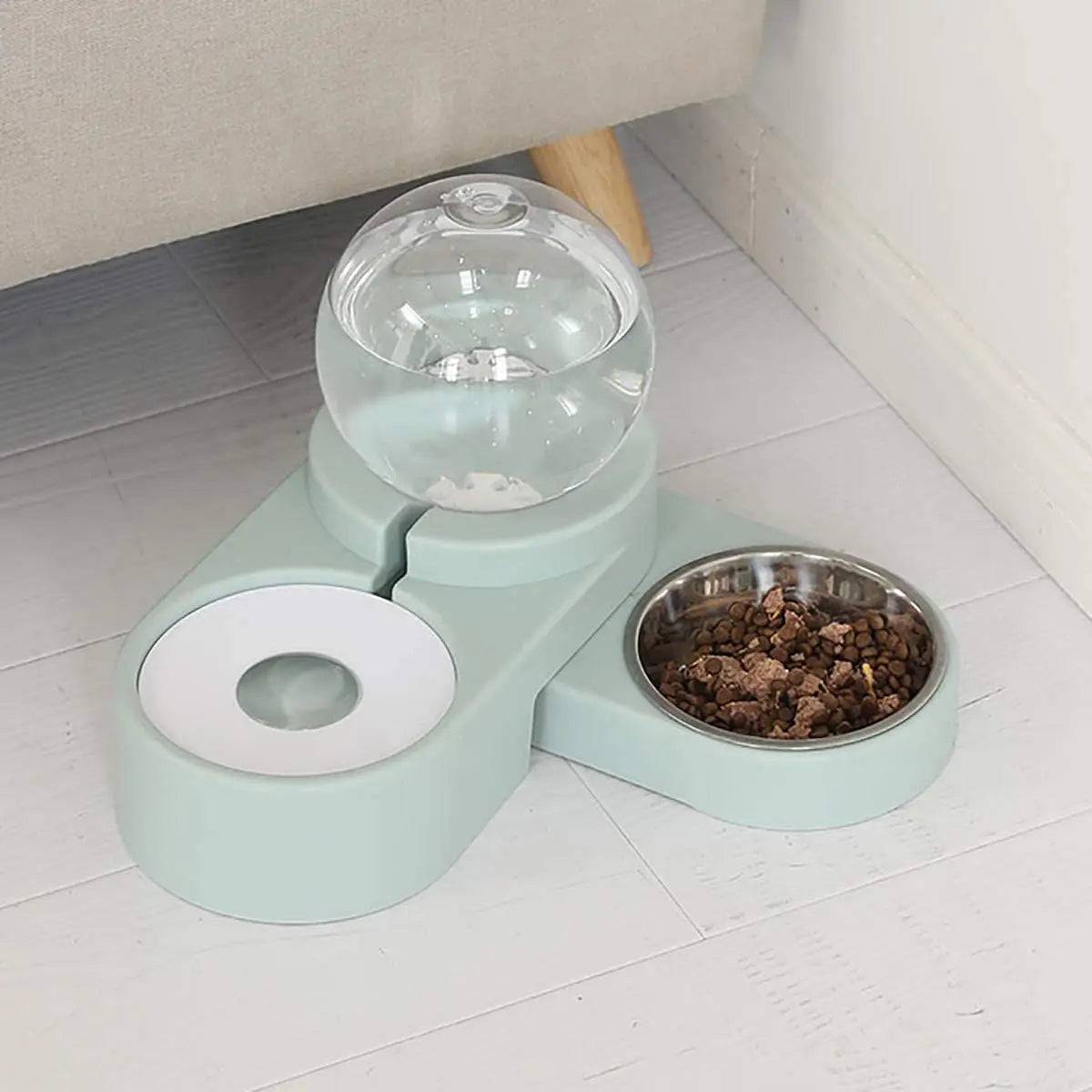 Light blue gravity water dispenser under a sofa edge with the stainless steel bowl filled with dry food