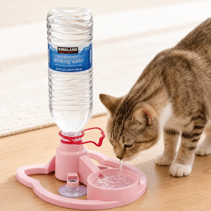 Pink gravity pet water dispenser on a wooden floor with an inverted water bottle and a tabby cat drinking from the bowl