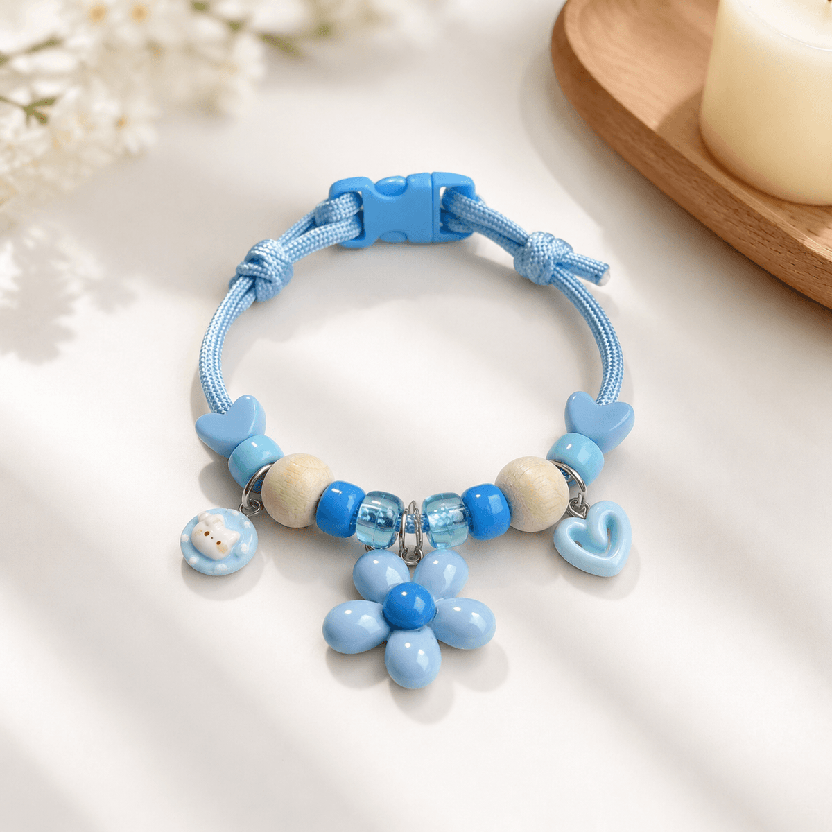Blue insect repellent pet collar with natural wood beads, a flower charm, a heart charm and a quick release buckle.