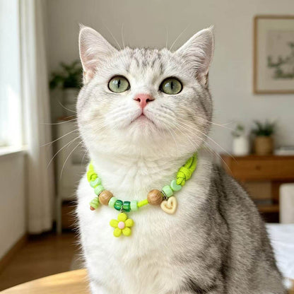 Silver tabby cat wearing the green insect repellent collar with its wood beads and flower charm sitting at the front of the neck.