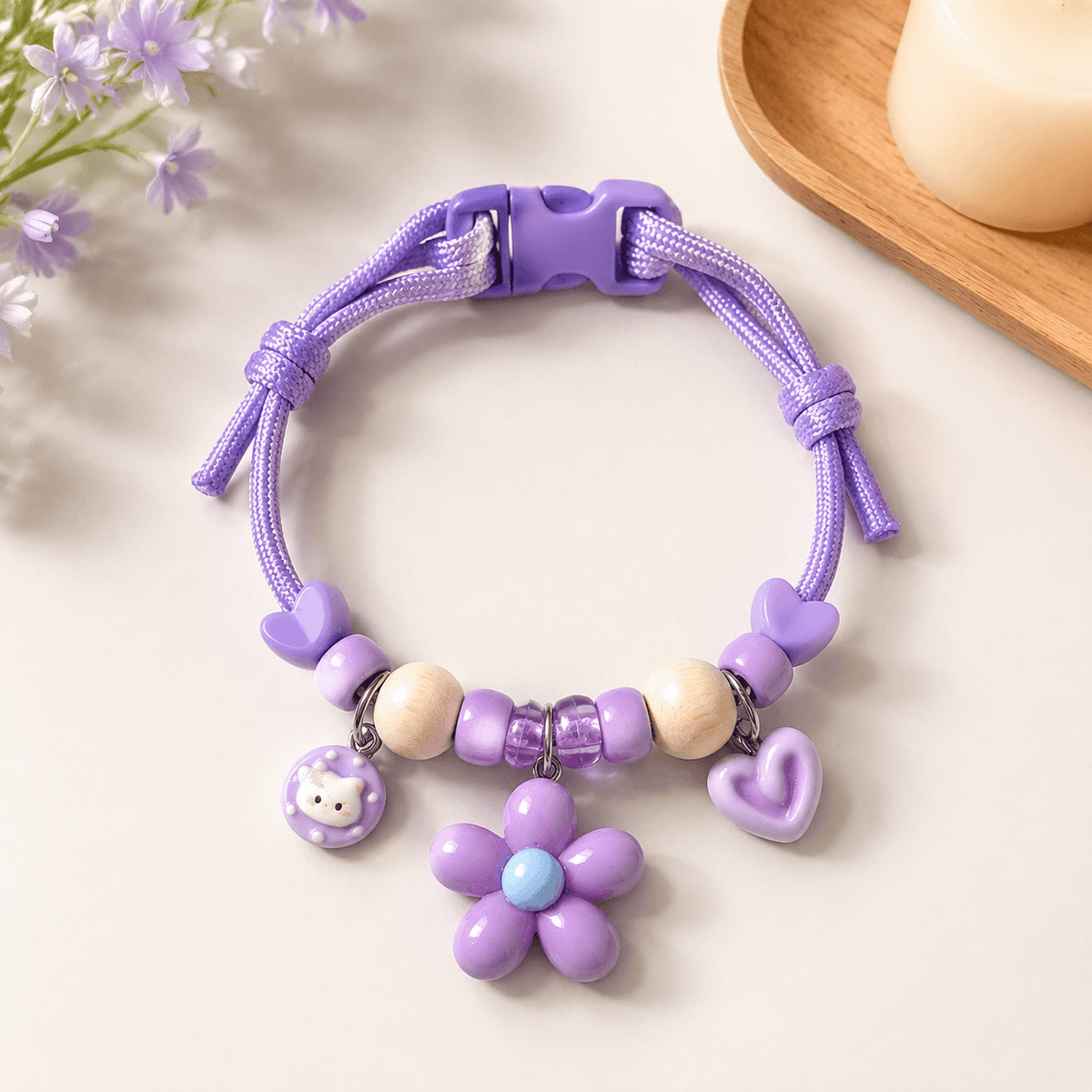 Purple insect repellent pet collar with natural wood beads, a flower charm, a cat charm and a quick release buckle.