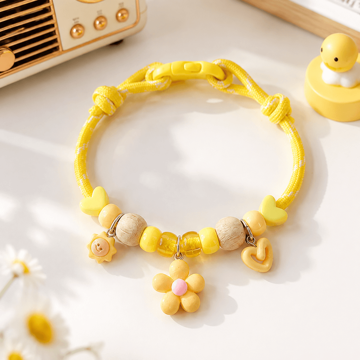 Yellow insect repellent pet collar with natural wood beads, a flower charm and a heart charm, shown flat on a pale surface.