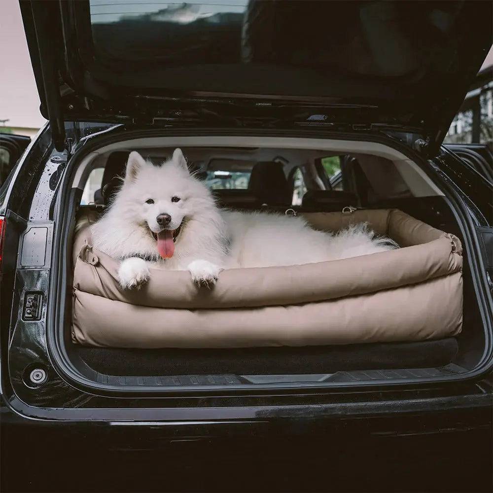 A samoyed stretched out in the Noblias large dog car seat bed sitting flat in an open SUV boot.