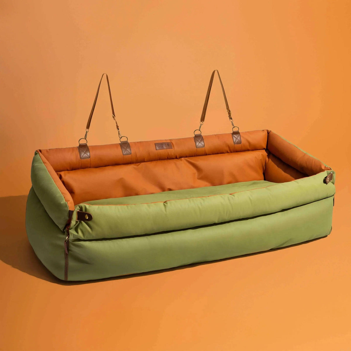 The Noblias large dog car seat bed in orange green, shown on its own with the headrest straps hanging.