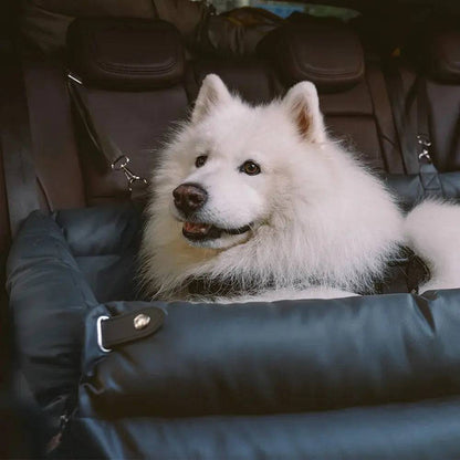 A samoyed resting its head on the wall of the black Noblias large dog car seat bed and looking out of the window.