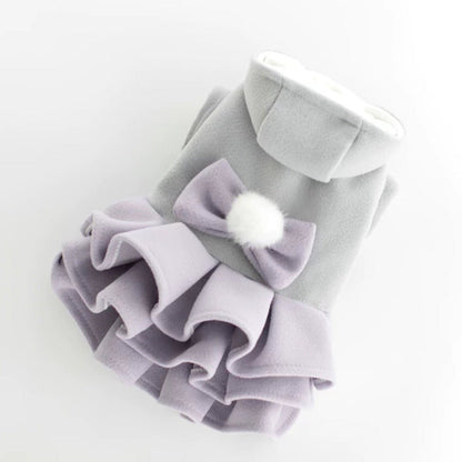 Purple layered dog dress laid flat with its white pom-pom bow