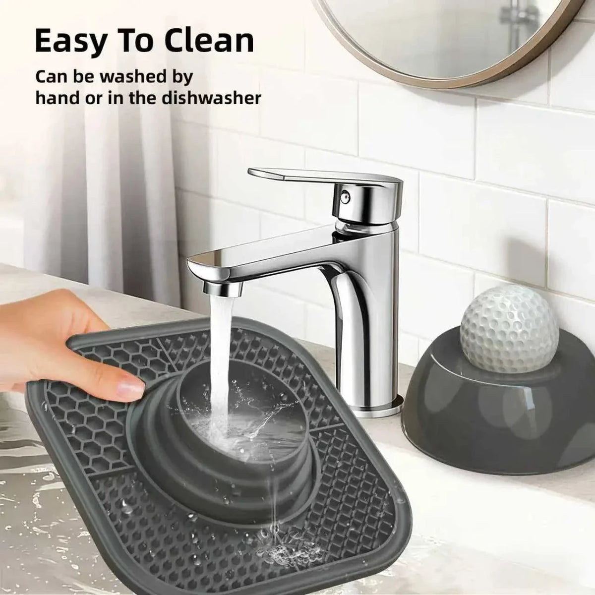 The Noblias lick mat slow feeder bowl being rinsed under a tap, showing the dome and mat separated for cleaning.
