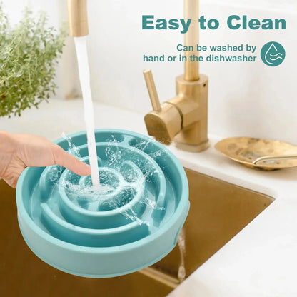 Blue maze slow feeder dog bowl rinsed under a tap, captioned washable by hand or in the dishwasher.