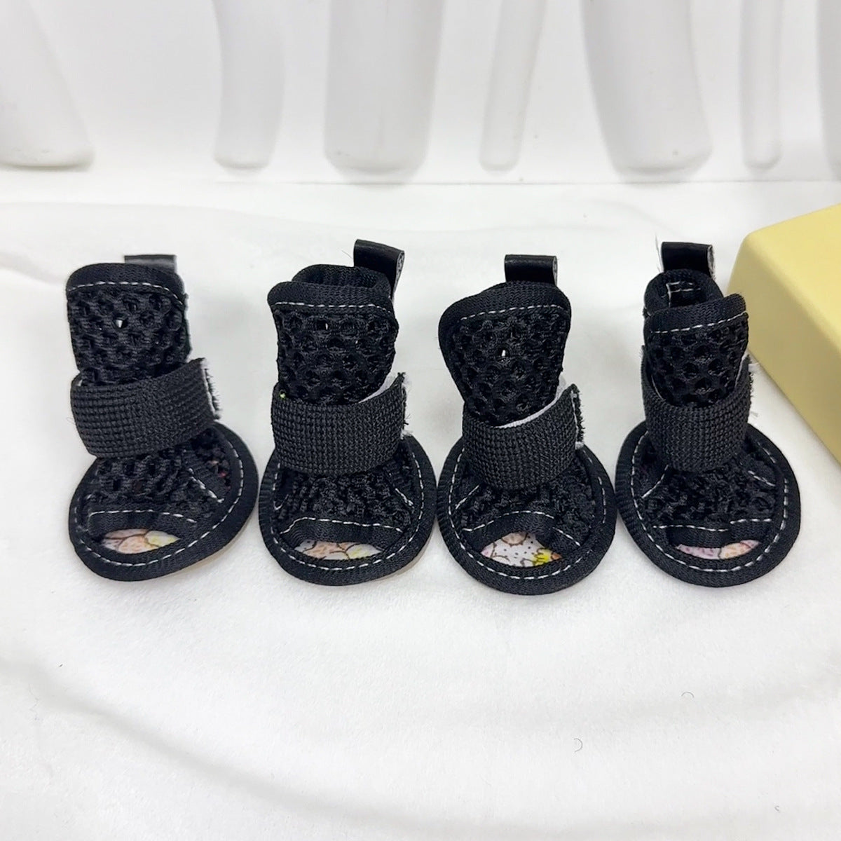 Set of four black Noblias mesh dog sandals with gray elastic straps and printed soles.