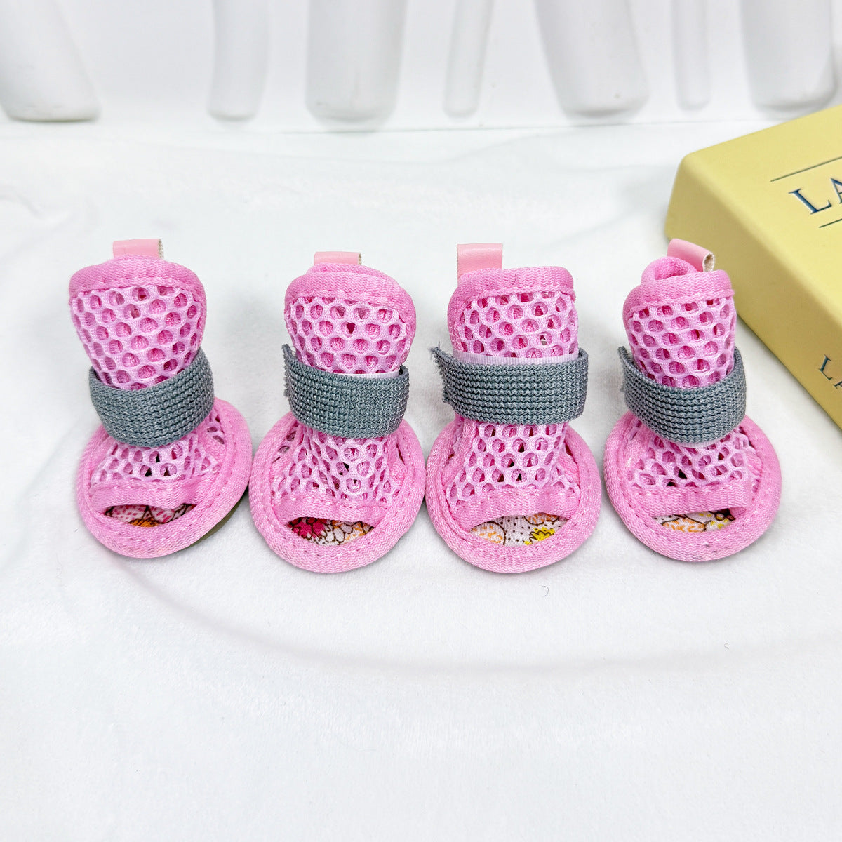 Set of four pink Noblias mesh dog sandals with gray elastic straps.