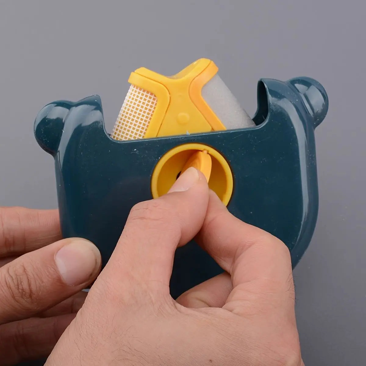 Navy mini pet hair remover brush with its bristle head lifted out of the shell.