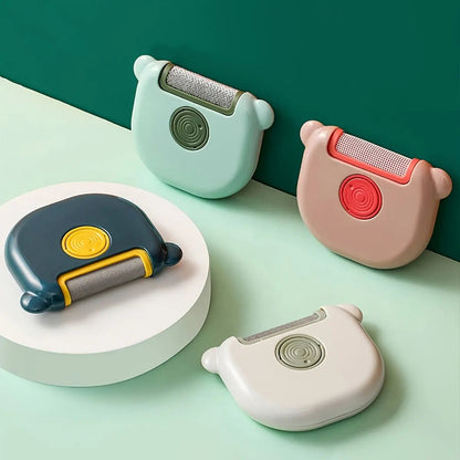 Mini pet hair remover brushes in green, pink, navy with yellow and cream on a two-tone background.