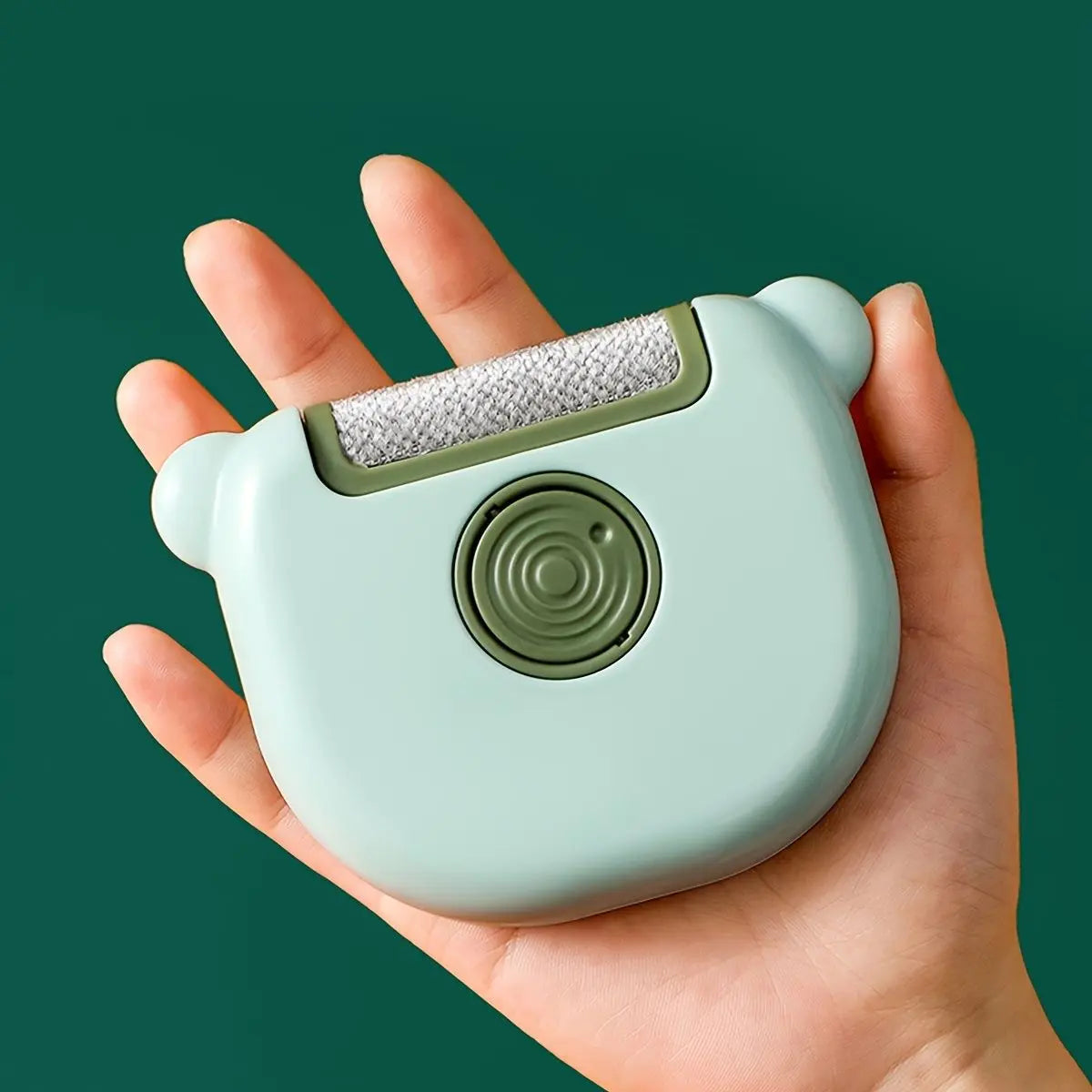 Green mini pet hair remover brush resting in the palm of a hand.