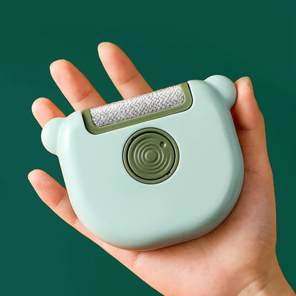 Green mini pet hair remover brush resting in the palm of a hand.