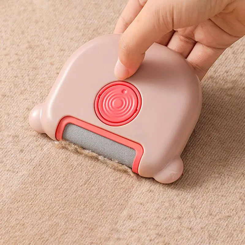 Hand pressing the pink mini pet hair remover brush onto a beige carpet.